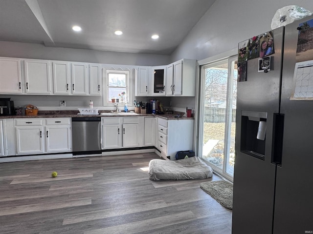 kitchen featuring a sink, lofted ceiling, appliances with stainless steel finishes, white cabinetry, and dark wood-style flooring