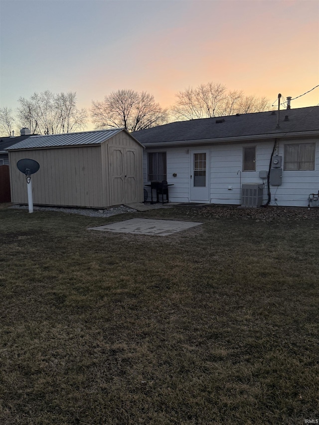 rear view of property with an outbuilding, a patio, a shed, a yard, and central AC unit