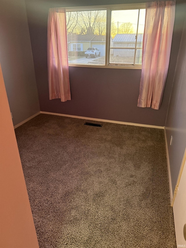 spare room featuring carpet flooring, a healthy amount of sunlight, and baseboards