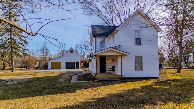 view of front of property featuring an outbuilding, a front yard, roof with shingles, covered porch, and a detached garage