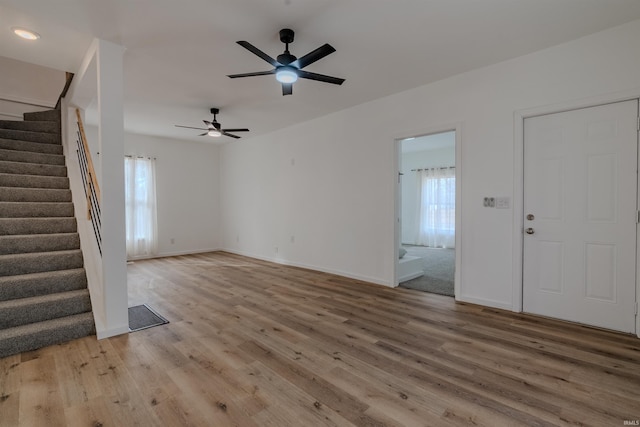 unfurnished living room with stairway, visible vents, baseboards, and light wood finished floors