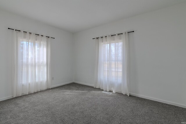 spare room featuring baseboards, carpet floors, and visible vents