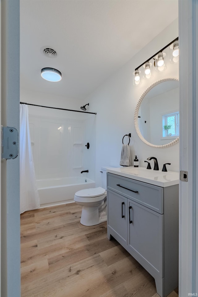 full bath featuring visible vents, toilet, shower / bath combo, wood finished floors, and vanity