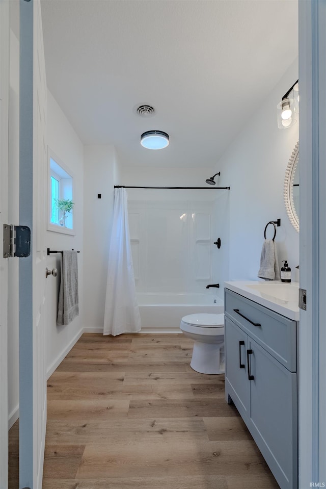 bathroom featuring vanity, wood finished floors, visible vents, shower / bath combination with curtain, and toilet