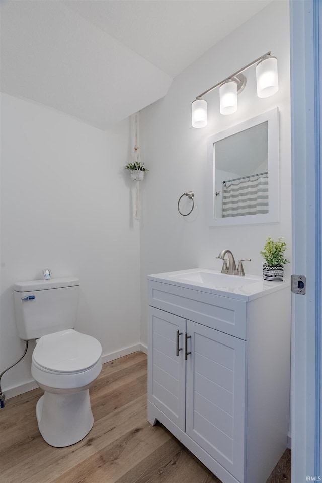 full bathroom with baseboards, toilet, wood finished floors, and vanity