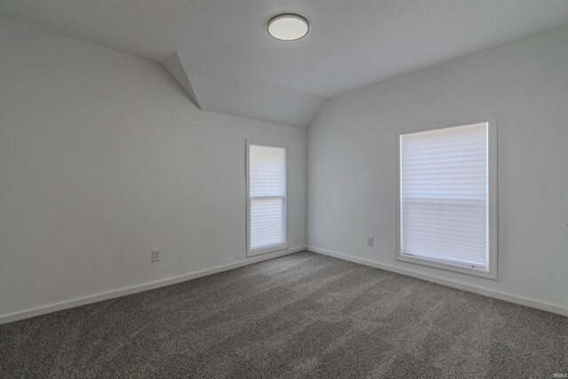 carpeted spare room with lofted ceiling and baseboards