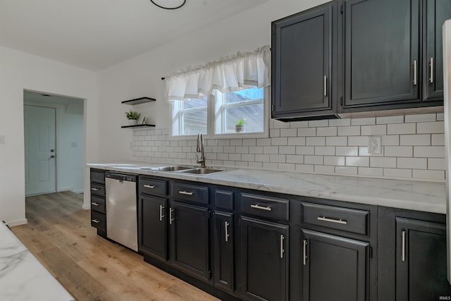 kitchen featuring light wood finished floors, backsplash, open shelves, dishwasher, and a sink