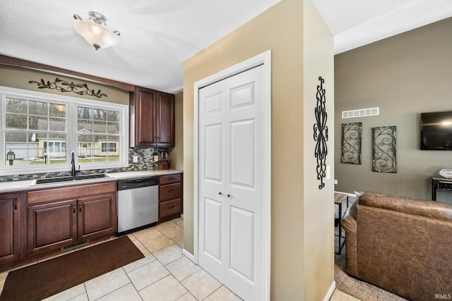 kitchen featuring light tile patterned floors, visible vents, a sink, decorative backsplash, and dishwasher