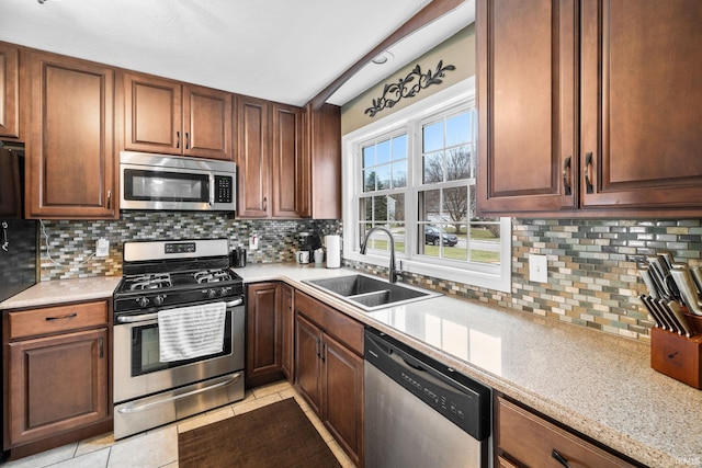 kitchen with a sink, light tile patterned floors, backsplash, and stainless steel appliances