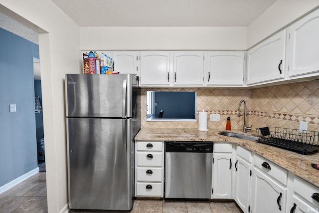 kitchen featuring tasteful backsplash, white cabinets, stainless steel appliances, and a sink