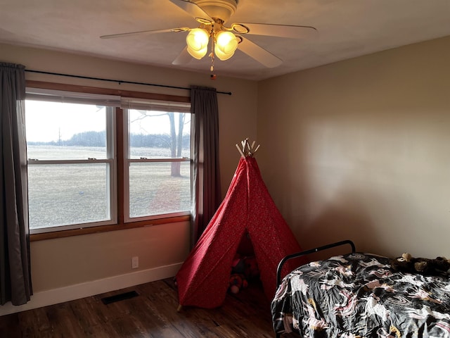 bedroom featuring ceiling fan, visible vents, baseboards, and wood finished floors