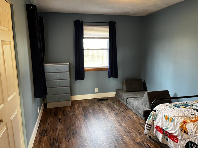 bedroom with visible vents, baseboards, and dark wood finished floors