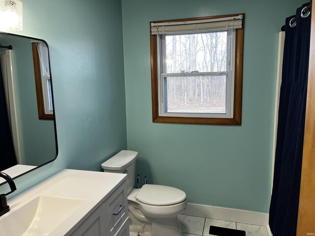 bathroom with vanity, toilet, baseboards, and marble finish floor