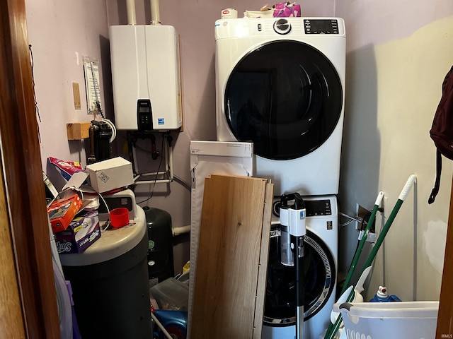 laundry area with laundry area, stacked washer / drying machine, and tankless water heater