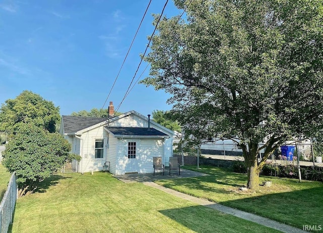 back of property featuring a yard, a chimney, and fence