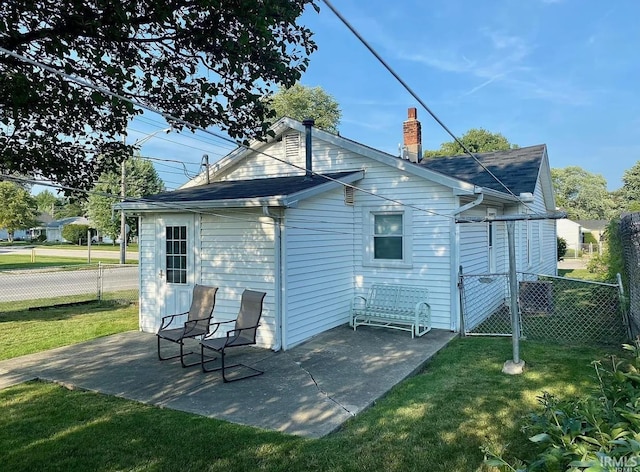 back of house with a patio, a chimney, a yard, and fence