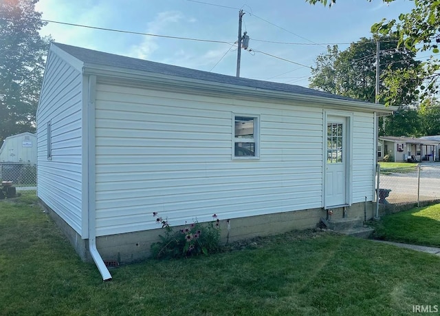 view of side of property featuring a lawn, roof with shingles, and fence