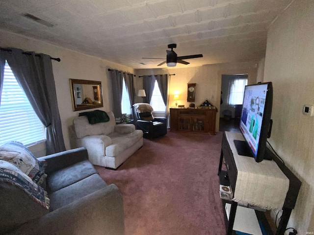 living room with visible vents, carpet floors, and ceiling fan