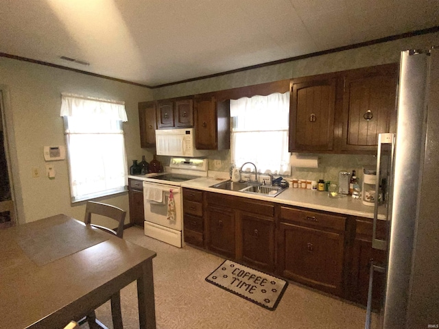 kitchen featuring a sink, white appliances, ornamental molding, and light countertops