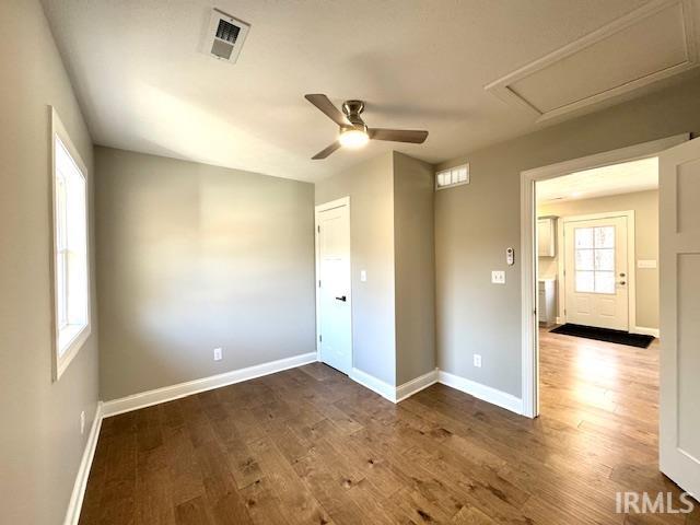 empty room with wood finished floors, visible vents, and baseboards