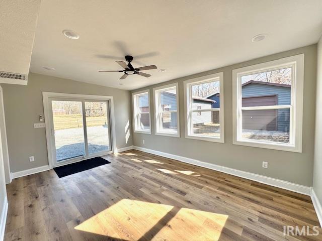 unfurnished sunroom featuring ceiling fan