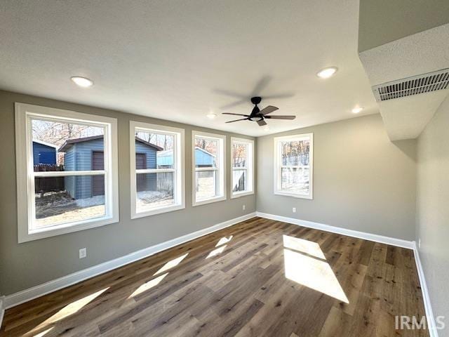 empty room with dark wood-style floors, baseboards, visible vents, recessed lighting, and ceiling fan