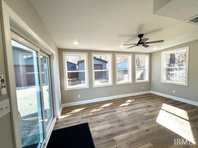 empty room with visible vents, wood finished floors, baseboards, and ceiling fan