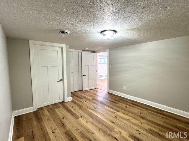 empty room with visible vents, baseboards, a textured ceiling, and wood finished floors