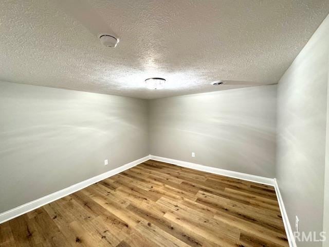 empty room featuring baseboards, a textured ceiling, and wood finished floors