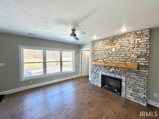 unfurnished living room featuring a large fireplace, a textured ceiling, and wood finished floors