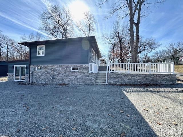 view of side of property with stone siding and fence