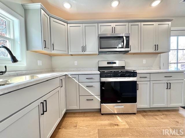 kitchen featuring light wood-type flooring, a sink, recessed lighting, stainless steel appliances, and light countertops