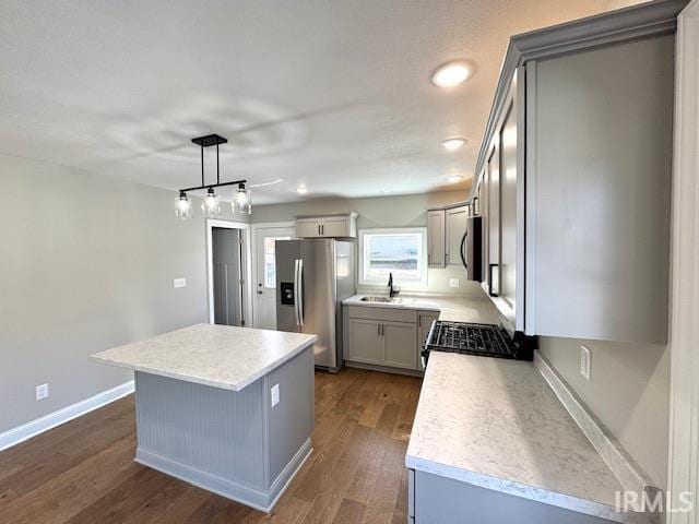 kitchen featuring dark wood finished floors, gray cabinets, a sink, stainless steel appliances, and a center island