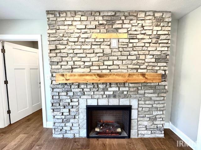 room details with a large fireplace, baseboards, and wood finished floors