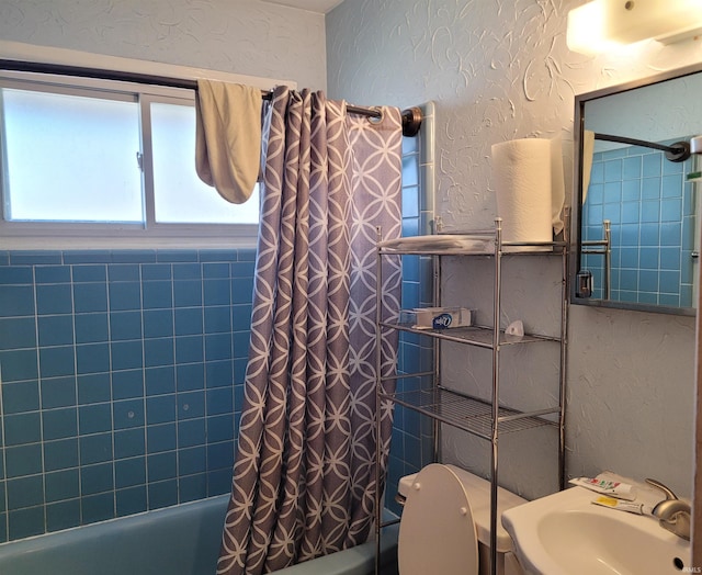 bathroom with a sink, shower / tub combo, and a textured wall