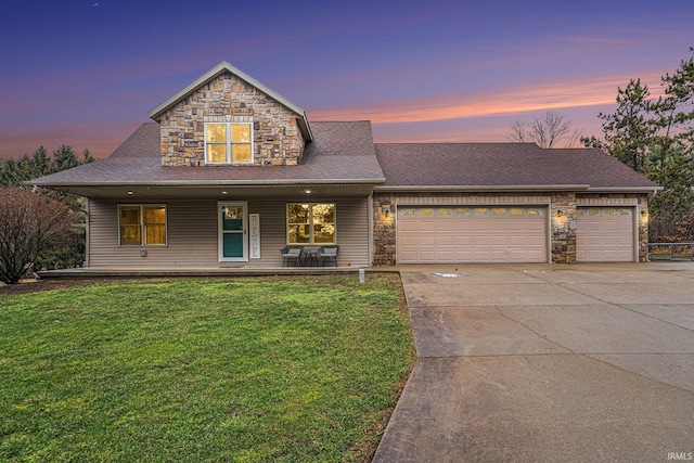 view of front of home featuring driveway, stone siding, a yard, covered porch, and an attached garage