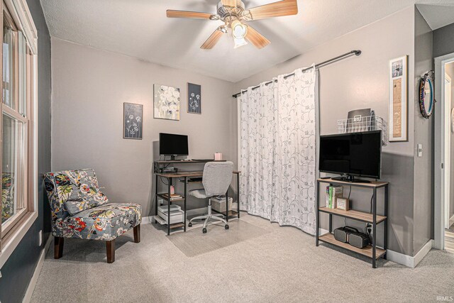 carpeted home office featuring baseboards and a ceiling fan