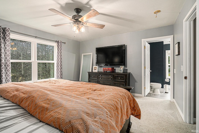 bedroom with connected bathroom, a ceiling fan, baseboards, and carpet floors