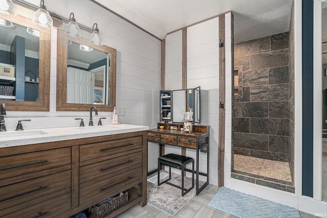 bathroom with double vanity, tiled shower, and a sink