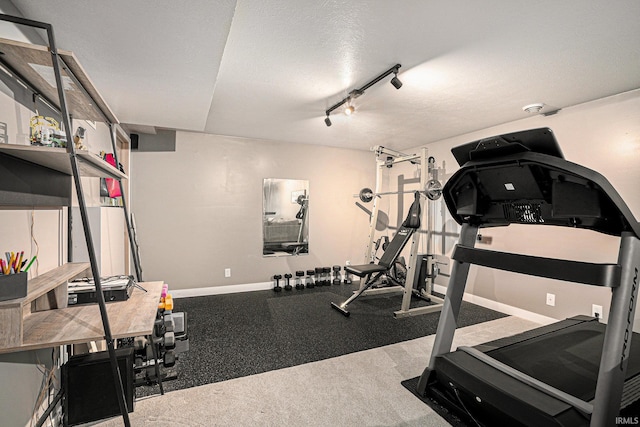 workout area featuring track lighting, a textured ceiling, and baseboards