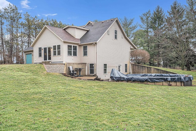 rear view of house with a covered pool, a lawn, roof with shingles, and an attached garage