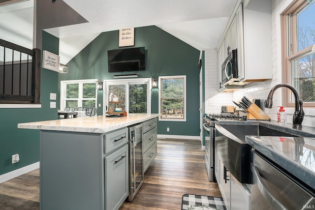 kitchen featuring beverage cooler, gray cabinetry, decorative backsplash, vaulted ceiling, and appliances with stainless steel finishes