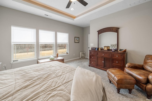 bedroom featuring a raised ceiling, light colored carpet, visible vents, and baseboards