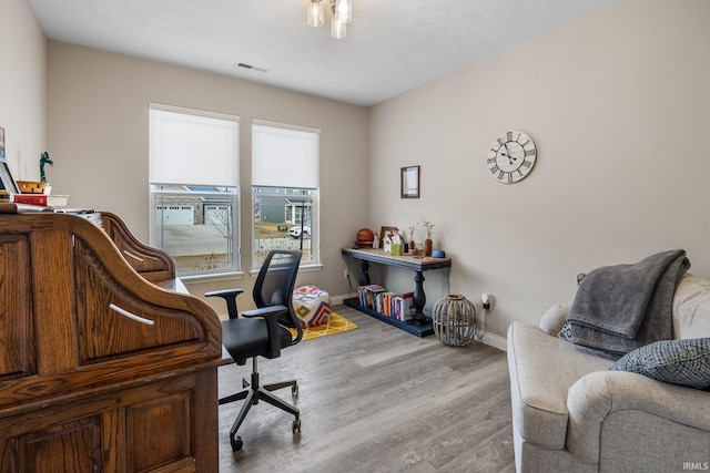 home office featuring light wood-style flooring, baseboards, and visible vents