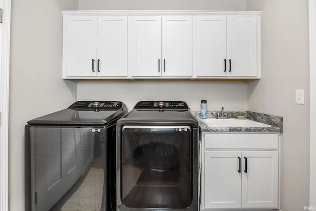 clothes washing area with washing machine and clothes dryer, cabinet space, and a sink