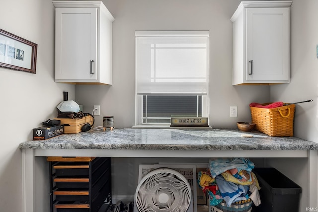 interior details featuring light stone counters and white cabinetry