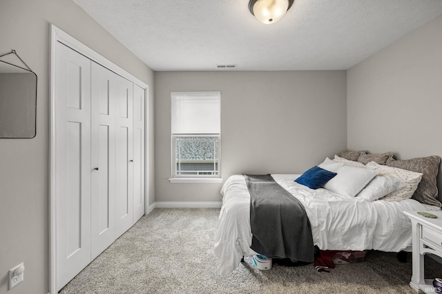 carpeted bedroom featuring visible vents, baseboards, a textured ceiling, and a closet