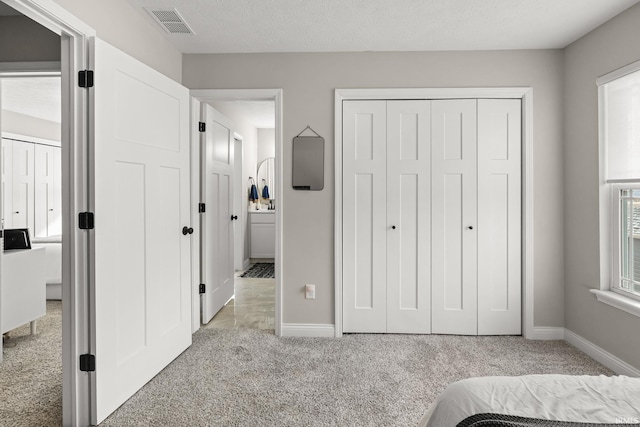 unfurnished bedroom with a textured ceiling, baseboards, visible vents, and light carpet