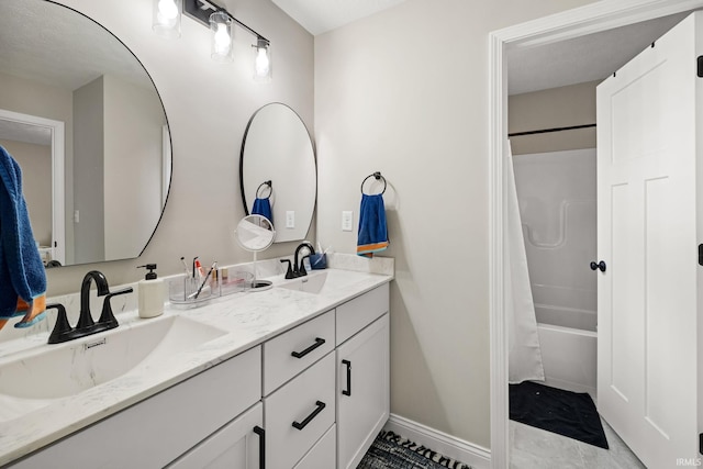 bathroom with double vanity, shower / bathtub combination with curtain, baseboards, and a sink