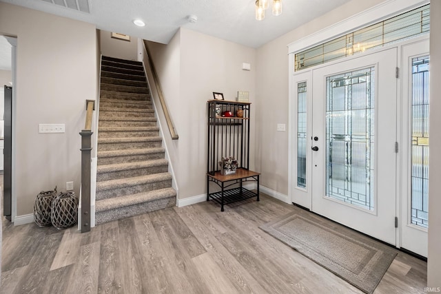 entrance foyer featuring stairway, visible vents, baseboards, and wood finished floors